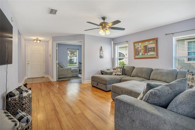 living room featuring ceiling fan, light hardwood / wood-style floors, and a healthy amount of sunlight