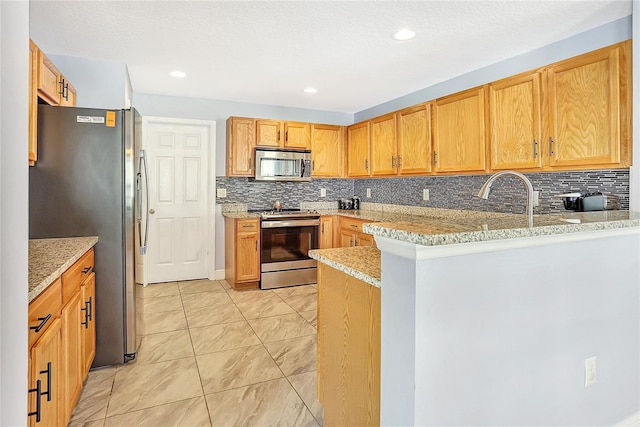 kitchen with kitchen peninsula, a textured ceiling, backsplash, appliances with stainless steel finishes, and light stone countertops