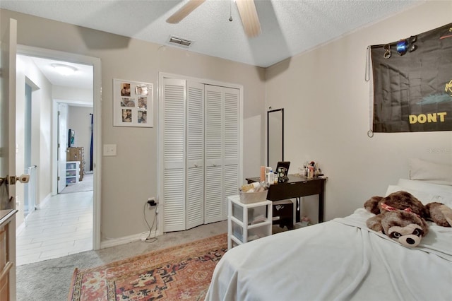 carpeted bedroom featuring a closet, ceiling fan, and a textured ceiling