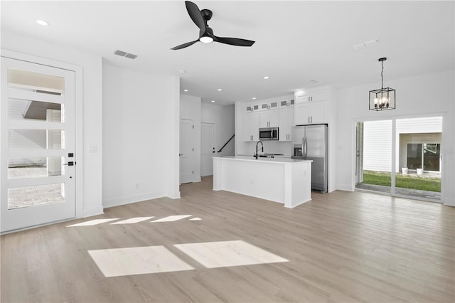 unfurnished living room featuring ceiling fan with notable chandelier, sink, and light hardwood / wood-style floors