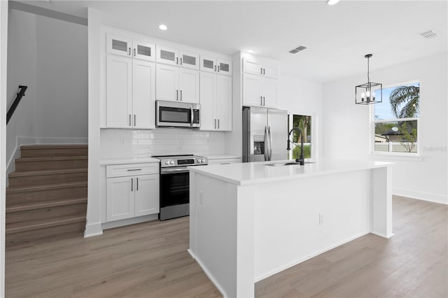 kitchen featuring stainless steel appliances, white cabinetry, a kitchen island with sink, and sink