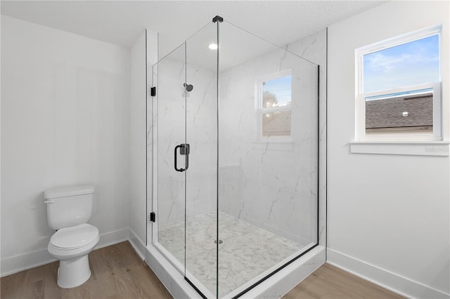 bathroom with toilet, a shower with shower door, and wood-type flooring