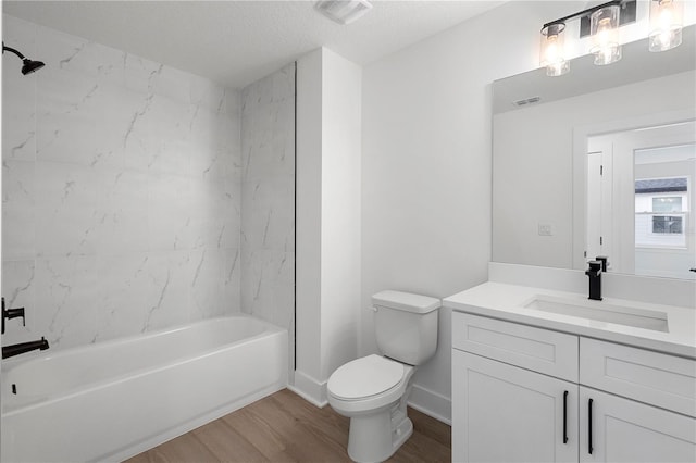 full bathroom featuring a textured ceiling, toilet, hardwood / wood-style flooring, vanity, and tiled shower / bath