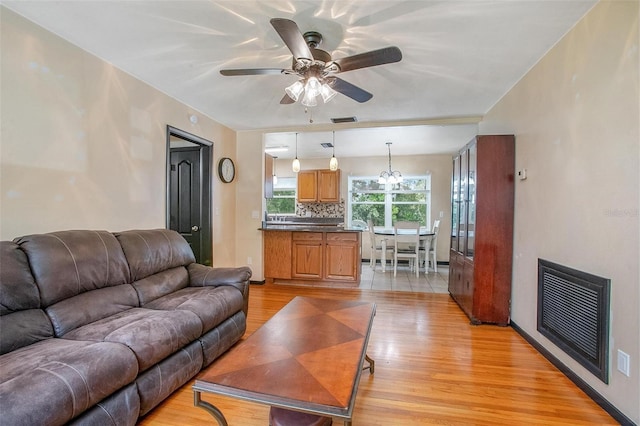 living room with light hardwood / wood-style flooring and ceiling fan with notable chandelier