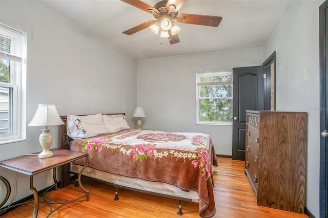 bedroom featuring light hardwood / wood-style flooring, ceiling fan, and multiple windows