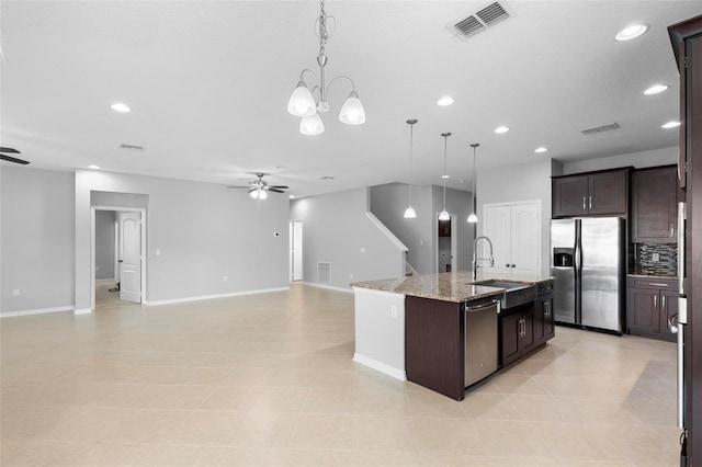 kitchen featuring dark brown cabinetry, sink, decorative light fixtures, a center island with sink, and stainless steel appliances