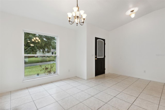 tiled empty room featuring an inviting chandelier and vaulted ceiling