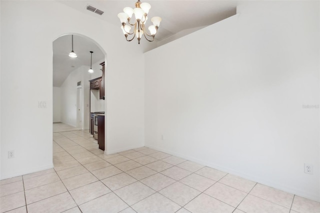 empty room featuring a notable chandelier, lofted ceiling, and light tile patterned floors