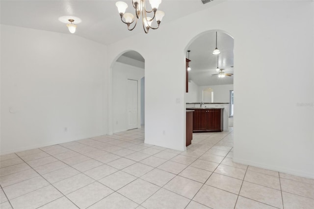 tiled empty room with ceiling fan with notable chandelier and lofted ceiling