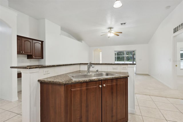 kitchen featuring ceiling fan, dark brown cabinetry, light carpet, sink, and lofted ceiling