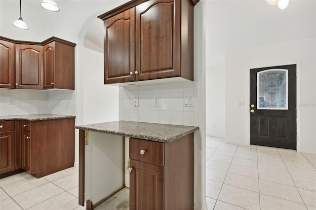 kitchen with decorative backsplash, dark stone countertops, pendant lighting, and light tile patterned floors