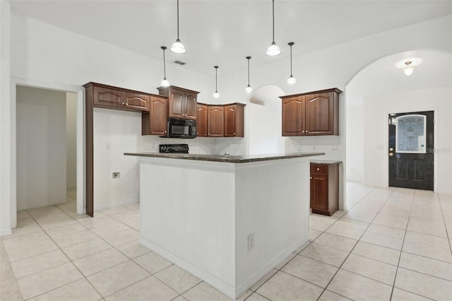 kitchen featuring light tile patterned flooring, a kitchen island, dark stone countertops, and decorative light fixtures