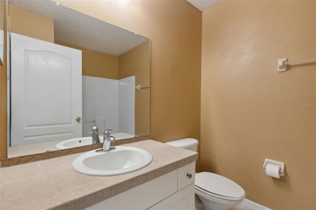 bathroom with vanity, toilet, and a textured ceiling