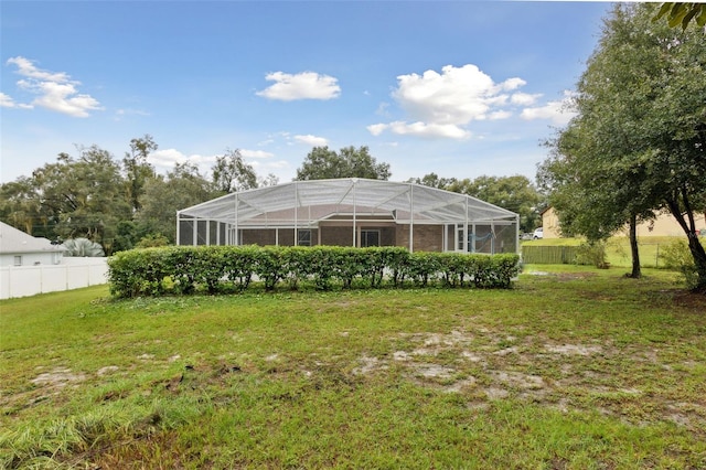 rear view of house with a yard and glass enclosure