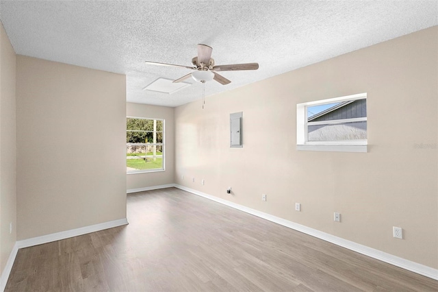 unfurnished room with wood-type flooring, ceiling fan, electric panel, and a textured ceiling