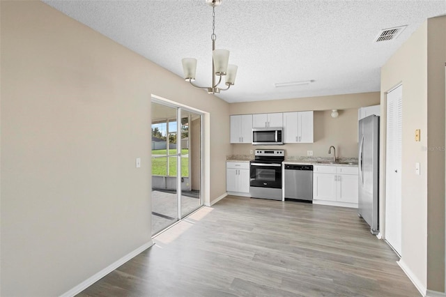 kitchen featuring appliances with stainless steel finishes, pendant lighting, light hardwood / wood-style floors, and white cabinets