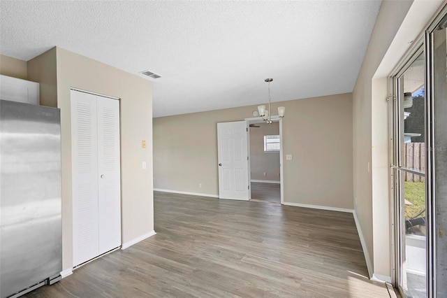 spare room with plenty of natural light, hardwood / wood-style floors, and a chandelier