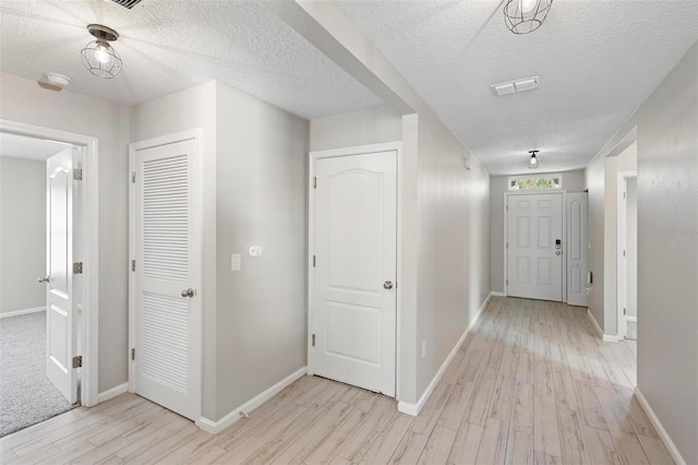 corridor featuring a textured ceiling and light hardwood / wood-style flooring