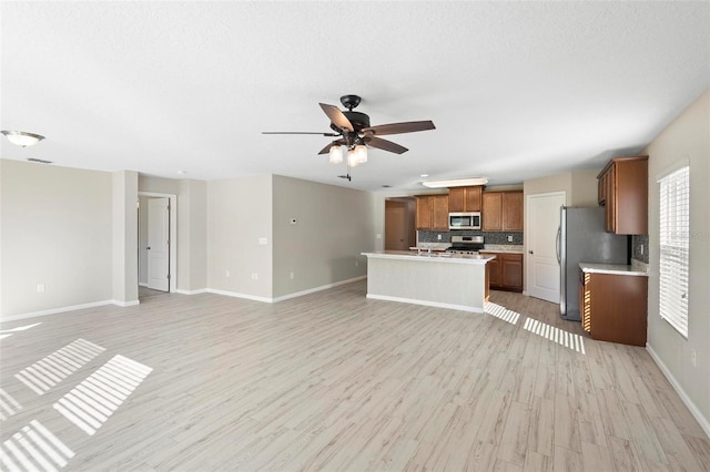 unfurnished living room featuring light wood-type flooring, ceiling fan, and a textured ceiling