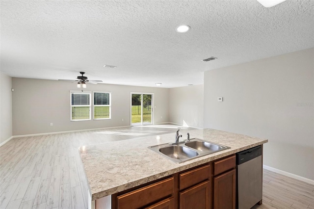 kitchen featuring an island with sink, light wood-type flooring, stainless steel dishwasher, and sink