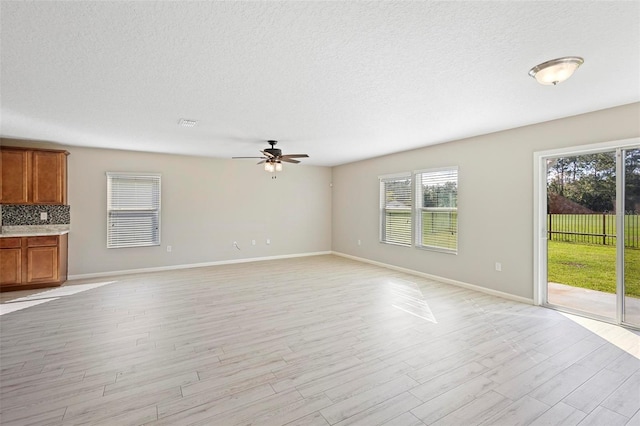 unfurnished living room featuring light wood-type flooring, ceiling fan, and a textured ceiling