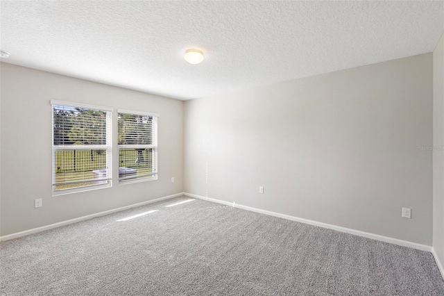 carpeted empty room featuring a textured ceiling