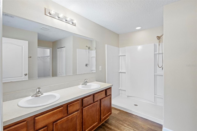 bathroom featuring walk in shower, vanity, a textured ceiling, and wood-type flooring