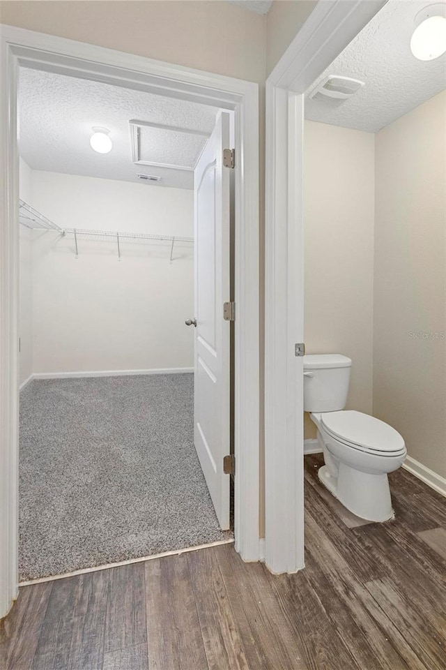 bathroom featuring wood-type flooring, a textured ceiling, and toilet