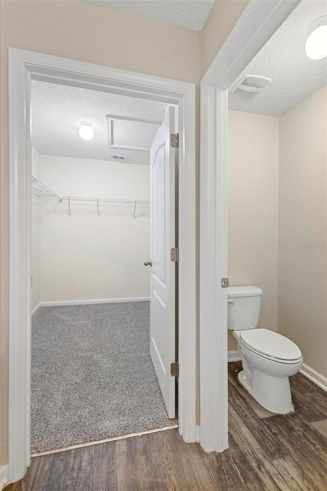 bathroom featuring toilet, wood-type flooring, and a textured ceiling