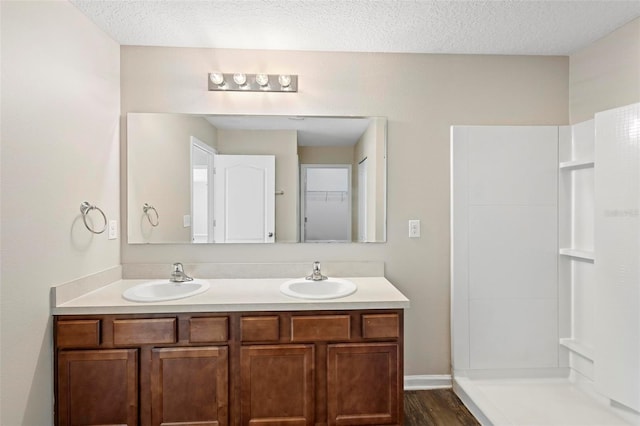 bathroom with a shower, hardwood / wood-style flooring, vanity, and a textured ceiling