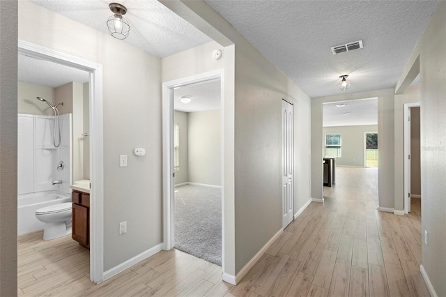 hallway featuring a textured ceiling and light wood-type flooring