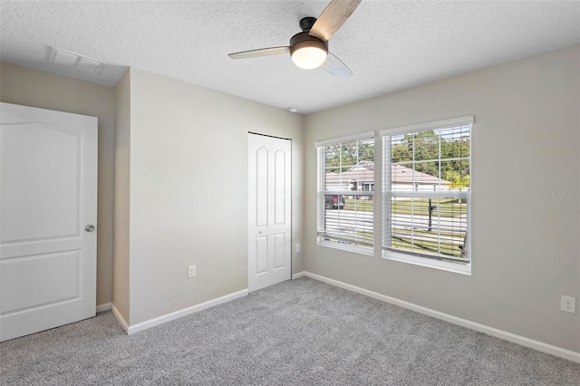 unfurnished bedroom with ceiling fan, a closet, carpet, and a textured ceiling