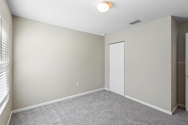 unfurnished bedroom with a textured ceiling, a closet, and carpet