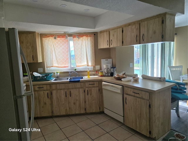 kitchen with white appliances, a textured ceiling, a wealth of natural light, and sink