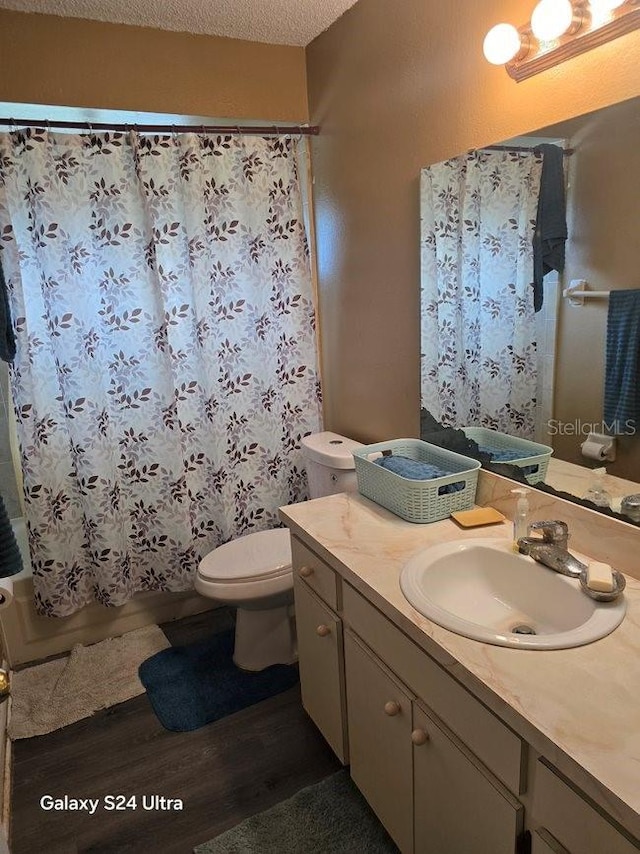 full bathroom featuring a textured ceiling, wood-type flooring, shower / bath combo with shower curtain, toilet, and vanity