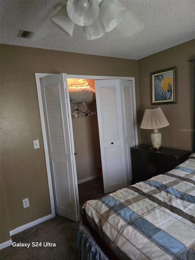 bedroom featuring dark colored carpet, a textured ceiling, and a closet