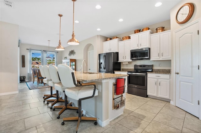 kitchen with a kitchen island with sink, hanging light fixtures, sink, white cabinetry, and appliances with stainless steel finishes