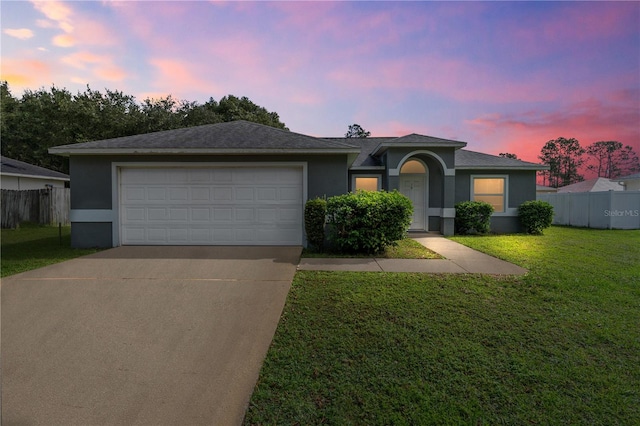 single story home featuring a garage and a lawn