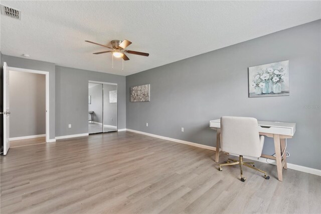 unfurnished office with light hardwood / wood-style floors, a textured ceiling, and ceiling fan