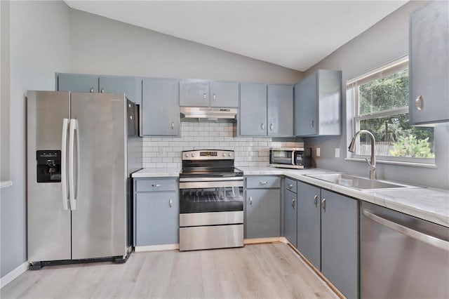 kitchen with lofted ceiling, appliances with stainless steel finishes, sink, and gray cabinetry