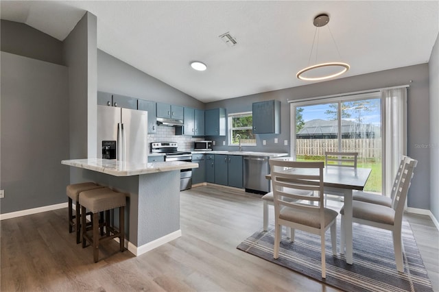 kitchen with stainless steel appliances, tasteful backsplash, lofted ceiling, hanging light fixtures, and sink