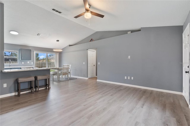 living room featuring light wood-type flooring, ceiling fan, lofted ceiling, and sink