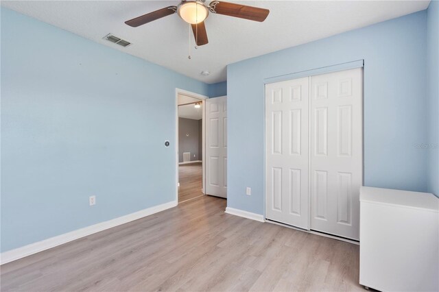 unfurnished bedroom featuring light wood-type flooring, ceiling fan, and a closet