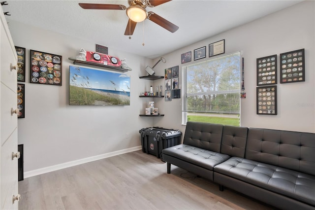 living room with light hardwood / wood-style floors, a textured ceiling, and ceiling fan