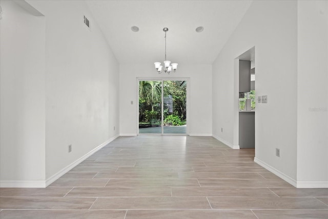 empty room with vaulted ceiling, light hardwood / wood-style flooring, and an inviting chandelier