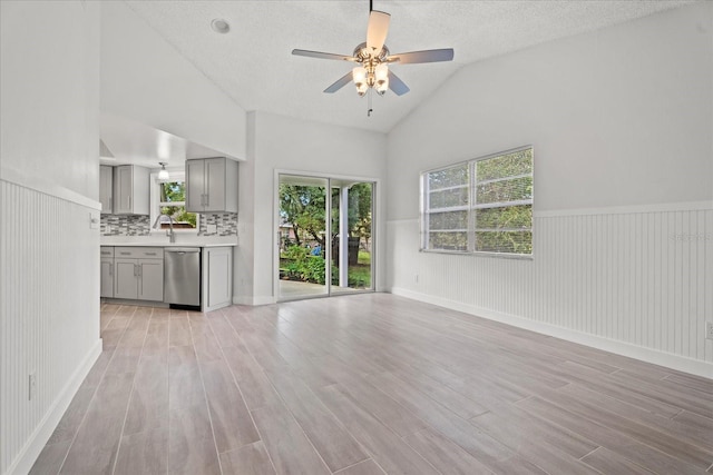 unfurnished living room with light hardwood / wood-style flooring, a textured ceiling, and wood walls