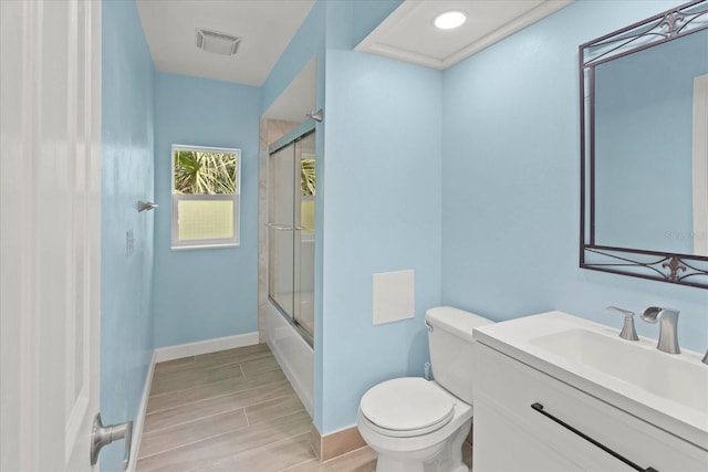 full bathroom featuring vanity, bath / shower combo with glass door, toilet, and hardwood / wood-style flooring