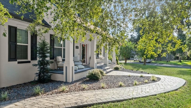 view of exterior entry featuring a lawn and covered porch