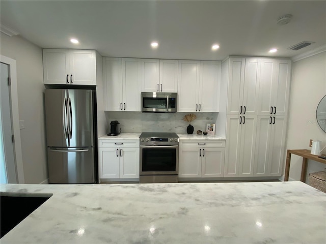 kitchen with light stone counters, white cabinets, and stainless steel appliances