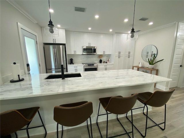 kitchen with light stone countertops, sink, white cabinets, and stainless steel appliances